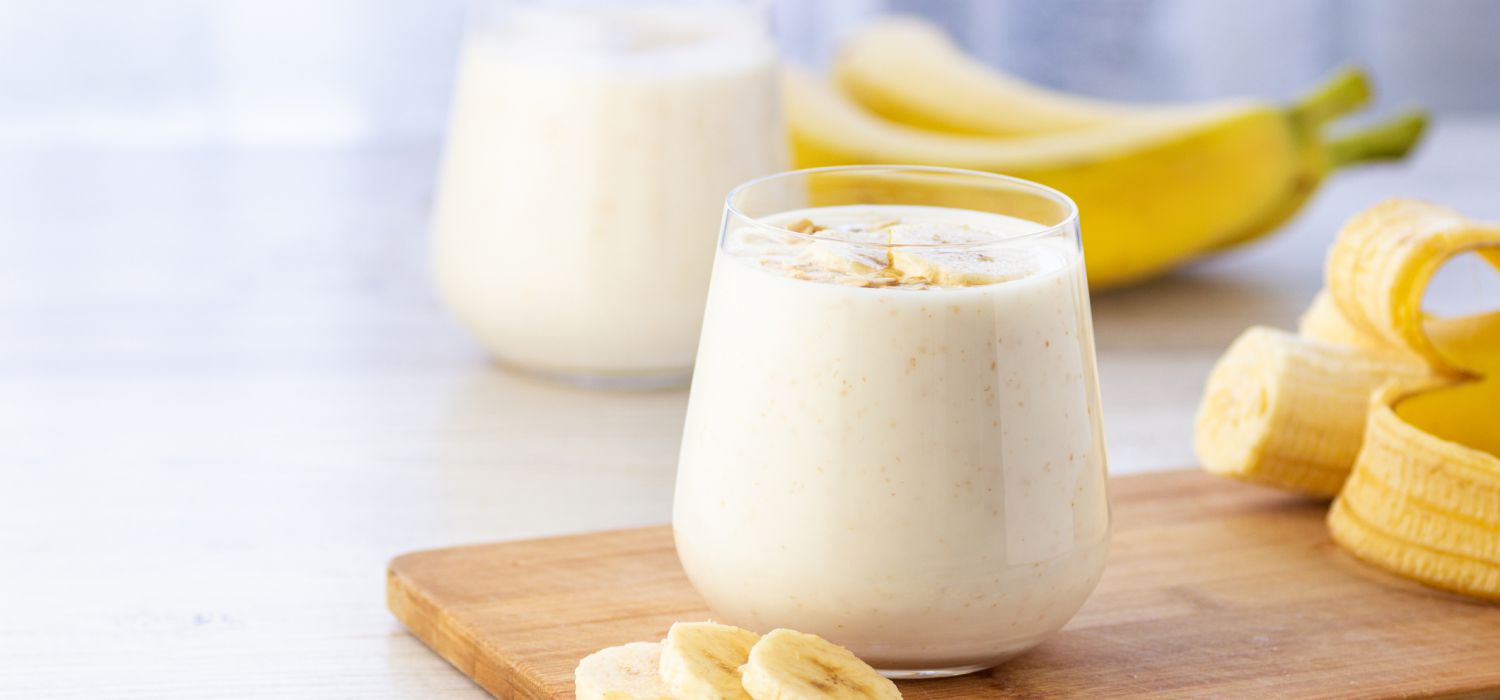 a glass of milk and a banana on a chop board