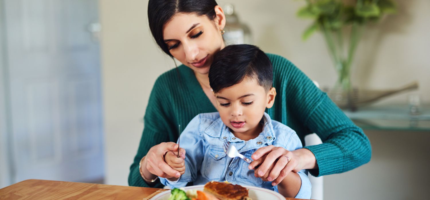 mother show son how to use knife and fork